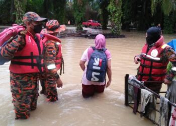 ANGGOTA bomba membantu penduduk yang terjejas akibat banjir di Teluk Intan, Perak semalam. - IHSAN BOMBA