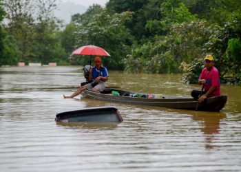 KAMARUDDIN Abdul Rashid, 55 (kanan) dan Salmi Salim, 42, melihat sebuah kereta yang tenggelam dalam banjir ketika mendayung sampan di Kampung Chemuak, di Dungun semalam. - PIX PUQTRA HAIRRY ROSLI