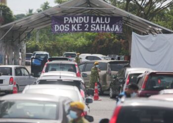 Kaunter vaksin pandu lalu...Anggota Rela mengawal kenderaan yang memasuki pusat pemberian vaksin (PPV) secara pandu lalu untuk menerima vaksin dos kedua di Dewan Sivik Bukit Payung, Marang pada Julai 2021. -UTUSAN/PUQTRA HAIRRY