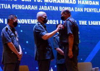 MOHAMMAD HAMDAN WAHID memakaikan pingat kepada salah seorang anggota JBPM dalam majlis di Butterworth, Pulau Pinang, hari ini.