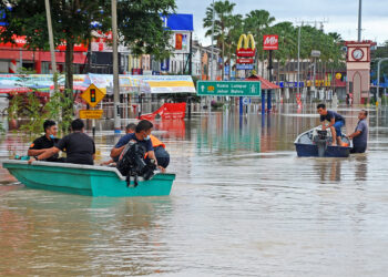 Penduduk menaiki bot ditengah-tengah pusat bandar Kota Tinggi, Johor, semalam yang dilanda banjir. - UTUSAN/RAJA JAAFAR ALI