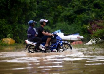 DUA lelaki meredah banjir yang semakin surut di Kemaman dan hampir 500 penduduk dibenarkan pulang ke rumah masing-masing. - FOTO/PUQTRA HAIRRY ROSLI