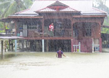 Seorang penduduk mengharung banjir dalam hujan lebat untuk pulang ke rumahnya di Kampung Sri Damai, Kuantan, semalam. – UTUSAN/SHAIK AHMAD RAZIF