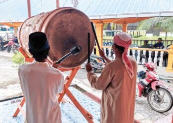 SHASUDDIN Ismail (kanan) menunjukkan cara memalu beduk di Masjid Ahmadiah Kampung Sungai Lancang di Bagan Datuk baru-baru ini. – UTUSAN/AIN SAFRE BIDIN