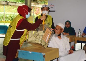 SHARIF KALAM dibantu petugas SPR mengundi di SMK Taman Pelangi, Johor Bahru.