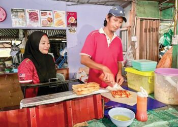 SUDIRMAN Amat bersama isteri, Malisa Omar berniaga gerai makan di Kampung Karakit, Pulau Banggi, Kudat di Sabah. -UTUSAN/SURAIDAH ROSLAN