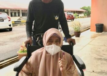 ENAH DORA dibantu anaknya, Jamil mengundi di SMK Alauddin Riayat Shah, Muar.