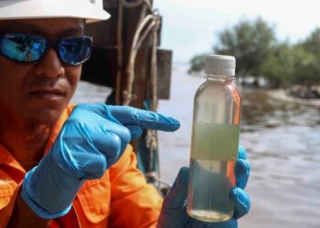 Juruteknik lapangan, Mohd. Syamsul Setapa menunjukkan sampel air yang diambil di muara Tanjung Sepat, Sepang bagi mengesan pencemaran pada 22 September lalu. – Utusan/FAISOL MUSTAFA