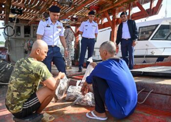 RASHIDILHADI Abd Rashid (berdiri, kiri) memeriksa sebahagian hasil laut dalam bot nelayan Vietnam yang ditahan selepas menceroboh perairan negeri ini di Kuala Terengganu, hari ini.