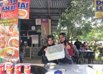 NORASIAH Abdul Rahman (kiri) bersama Nurul Nadia Ismail menunjukkan bekas tepung roti canai yang habis di Restoran Roti Canai Janda, Pokok Sena, Kedah, semalam.