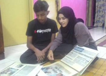 MOHAMMAD Nursyabil Syakirin Mohammad Nordin dan Norhayati Abu Bakar melihat keratan akhbar mengenai laporan kes culik membabitkan dirinya ketika berusia enam hari di Sungai Lalang, Sungai Petani, Kedah, kelmarin.