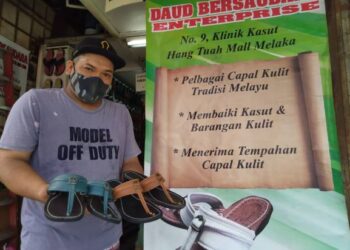 MOHAMMAD Nazri Rashid menunjukkan capal yang dijual pada harga RM79 hingga RM149 sepasang di kedai Daud Bersaudara Enterprise di Melaka. - FOTO/MUHAMMAD SHAHIZAM TAZALI