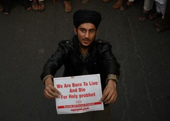 Seorang lelaki menunjukkan poster cintakan nabi dalam tunjuk perasaan membantah tindakan Perdana Menteri Perancis, Emmanuel Macron menyokong kartun menghina Nabi Muhammad SAW di Lahore, Pakistan. – AFP