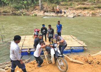 PENDUDUK Orang Asli menaiki rakit buluhmenyeberangi Sungai Perias di Pos Tohoi, Gua Musang, Kelantan. - UTUSAN/AIMUNI TUAN LAH