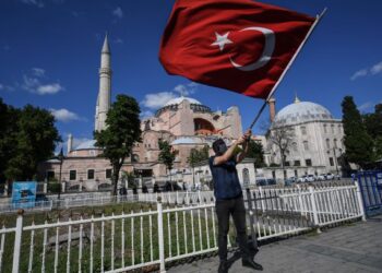 SEORANG lelaki mengibarkan bendera Turki di luar Hagia Sophia meraikan keputusan mahkamah menukar kembali muzium itu kepada masjid. - AFP