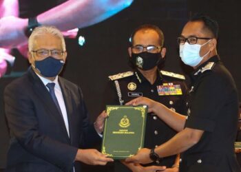 HAMZAH Zainudin menyampaikan Anugerah Perkhidmatan Cemerlang Jabatan Imigresen Tahun 2020 kepada Pengarah Bahagian Pekerja Asing, Mohammad Abiddin Abd. Rahman (kanan) di Putrajaya. - UTUSAN/FAISOL MUSTAFA