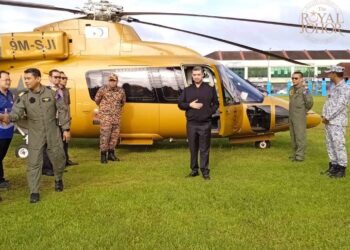 TUNKU IDRIS ISKANDAR SULTAN IBRAHIM (tengah) membantu membawa bekalan makanan dan barangan kebersihan diri untuk mangsa banjir di Chaah, Segamat menggunakan helikopter.