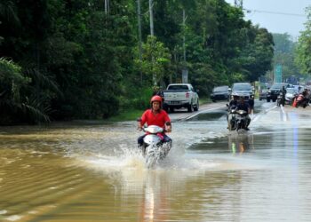 BEBERAPA penunggang motosikal meredah banjir di Jalan Yong Peng-Chaah berdekatan Kampung Temehel , Yong Peng, Batu Pahat.