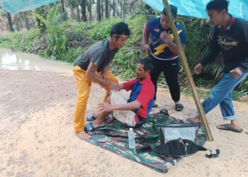 MAHAT MAYA (duduk) dibantu penduduk Kampung Orang Asli Pucur selepas bot dinaiki dilibas buaya di Sungai Bahai, Kahang.