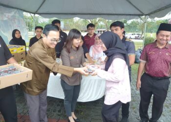 TEO NIE CHING (tengah) mengedarkan bubur lambuk dan kurma kepada orang ramai termasuk para penuntut di UTM, Skudai.