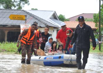 PANDAK AHMAD membantu menarik bot penyelamat yang dinaiki oleh penduduk dalam kejadian banjir di Kampung Baru Muafakat, Iskandar Puteri.