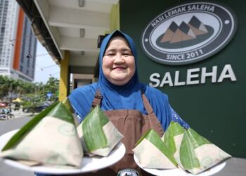 Saleha Abdullah menunjukkan nasi lemak di hadapan restorannya di Sri Rampai, Kuala Lumpur baru-baru ini.