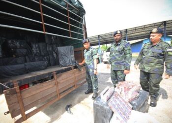 KU Majidin Che Ku Jusoh (kiri) bersama pegawainya menunjukkan rokok seludup yang dirampas Pasukan Gerakan Am di sempadan Malaysia-Thailand di Markas Taktikal Lubok Setol, Rantau Panjang, Kelantan. - UTUSAN/ZULHANIFA SIDEK