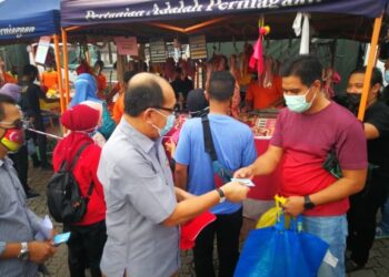 IZHAM Hashim menyampaikan kupon subsidi untuk membeli daging kepada pengunjung Pasar Tani Stadium Malawati Shah Alam. - FOTO/ABDUL RAZAK IDRIS