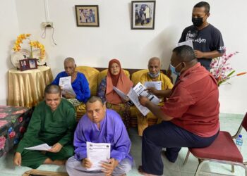 MOHD. Hamidi Mad Tap (kanan) melihat borang permohonan bantuan JKM sambil diperhatikan Zainah Ali di Taman Sri Penggaram, Batu Pahat, Johor. – UTUSAN/MOHAMAD FAHD RAHMAT