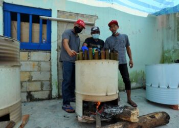 MOHD. Rosli Abd. Rahman (kiri) melihat kerja-kerja membakar lemang dengan menggunakan tong dram yang diubah suai oleh di Stulang Baru, Johor Bahru di Johor. - UTUSAN/RAJA JAAFAR ALI