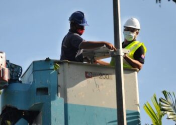 ASMAN Shah Abd. Rahman (kanan) memasang lampu solar sempena Program Datuk Bandar MBPG Bersama Komuniti Kampung Perigi Acheh, Pasir Gudang di Johor. - UTUSAN/RAJA JAAFAR ALI