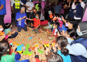 ISMAIL Sabri Yaakob menyantuni kanak-kanak yang ditempatkan di PPS sambil diperhatikan  Menteri Besar Johor, Datuk Hasni Mohammad ketika mengadakan lawatan ke Pusat Pemindahan Banjir di Dewan Kampung Tandung, Buloh Kasap, Segamat, Johor. -UTUSAN/RAJA JAAFAR ALI