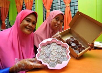 NORANI Mohd. Halel (kiri) bersama Pengurus Pusat Komuniti Desa Melayu Raya, Nor Rimezawani Jamaian menunjukkan sabun kelulut MR Trigona Nursery di Kampung Melayu Raya, Pekan Nenas, Pontian. – UTUSAN/RAJA JAAFAR ALI