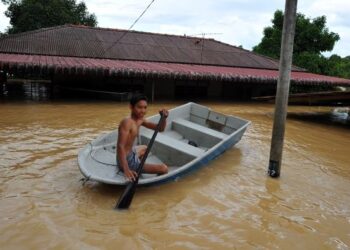 SEORANG penduduk mendayung sampan di hadapan rumahnya yang dilanda banjir di Kampung Chodan, Segamat. - UTUSAN/RAJA JAAFAR ALI