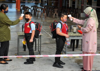 Darius Ishqisah Mohd Ishak (dua dari kiri) dan Darris Ishqish (dua dari kanan) kedua-dua tahun tiga diimbas suhu oleh guru sebelum memasuki kelas pada sesi kemasukan fasa 4 PPN di SK Angkatan Tentera, Johor Bahru disini. UTUSAN/RAJA JAAFAR ALI