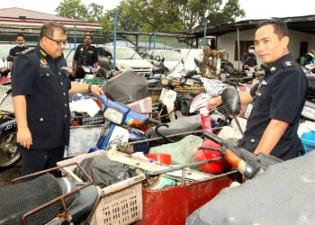 AZMIL Zainal Adnan (kiri) bersama seorang pegawai JPJ memeriksa motosikal milik warga asing yang diubah suai untuk mengutip barangan lusuh dalam operasi khas jabatan itu di Johor Bahru, semalam. - UTUSAN/BAAZLAN CHE IBRAHIM