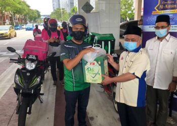 ABDUL Aziz Jusoh menyerahkan sumbangan kepada penghantar makanan di hadapan pintu utama Masjid Tunku Mizan Zainal Abidin, Putrajaya. - FOTO/SUBKHI SUDARJI