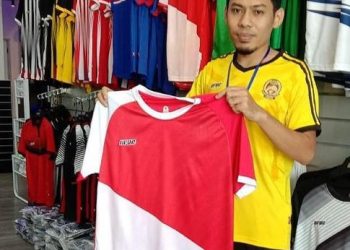 SEORANG kakitangan PUC Sport menunjukkan jersi akan dilelong secara besar-besaran sempena menyambut Hari Kebangsaan Ke-63 Isnin ini. - FOTO/ZULHANIFA SIDEK