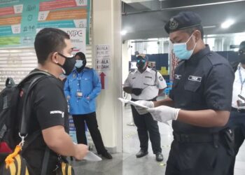 ANGGOTA polis memeriksa dokumen perjalanan seorang penumpang feri di Terminal Feri Penumpang Langkawi yang beroperasi semula, hari ini. - UTUSAN/NUR AMALINA AZMAN