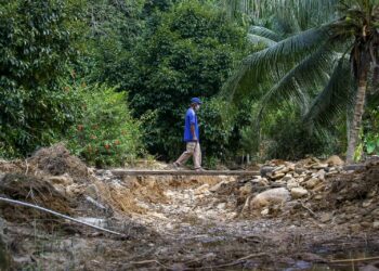 Penduduk melintasi saliran anak sungai  baharu yang terbentuk di Kampung Jawa, Batu Hampar di Yan. -
UTUSAN/ SHAHIR NOORDIN