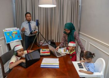 Pasangan guru, Zulhazmi Awang Kechik dan Nur Adilah Yusof membuat rakaman video bagi melengkapi modul Pengajaran dan Pembelajaran di Rumah (PdPR) manakala tiga anak mereka mengikuti kelas dalam talian di Kuala Nerang, Kedah, kelmarin. – Utusan/Shahir Noordin