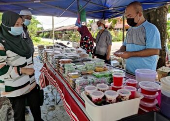 MOHD. Zaini Mohd. Zainal (kanan)  membantu salah seorang adiknya yang berniaga kuih-muih di sebuah gerai di Taman Ria, Sungai Petani, Kedah. – UTUSAN/ZAID MOHD. NOOR