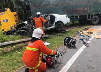 ANGGOTA bomba menggunakan peralatan menyelamat khas untuk mengeluarkan mangsa yang tersepit  dalam kereta setelah terlibat kemalangan dengan sebuah treler di Jalan Gelung Pepuyu dekat Parit hari ini.  - IHSAN JBPM PERAK