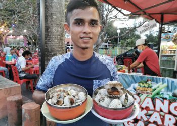 MOHAMAD Nazariezal Arif Daud menunjukkan kerang yang dijual di gerai Penyu Corner di Pantai Batu Buruk, Kuala Terengganu.