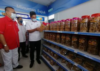 TENGKU Ahmad Nadzri Tengku Musa (kanan) melihat produk-produk usahawan Ketengah yang dipasarkan di Kedai Mart, stesen minyak Petron Pengkalan Gawi, di Tasik Kenyir, Hulu Terengganu, semalam. – UTUSAN/NOOR HAYATI MAMAT