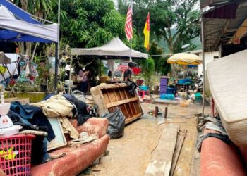 PENDUDUK membersihkan lumpur dan membuang barangan yang rosak akibat banjir di Kampung Lembah Jaya Ampang, semalam. – FOTO/FAUZI BAHARUDIN