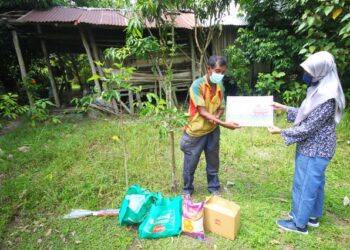 ABDULLAH Busu yang tinggal sebatang kara di sebuah bangsal di Kampung Bukit Pak Junuh, Pasir Mas, menerima sumbangan daripada wakil MMSB, Rosliza Mohamed, baru-baru ini. – UTUSAN/ZULHANIFA SIDEK