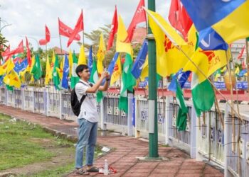 SEORANG lelaki melintasi deretan bendera parti-parti politik yang bertanding pada Pilihan Raya Umum Ke-15 yang di pasang di Lubok Jong, Pasir Mas, Kelantan. - UTUSAN/KAMARUL BISMI KAMARUZAMAN