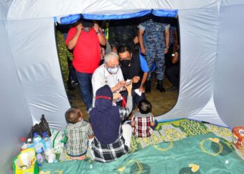 MANGSA banjir menunjukkan gambar rumahnya yang musnah selepas dilanda banjir kepada Perdana Menteri ketika  melawat Pusat Pemindahan Sementara (PPS) di bandar Mentakab, hari ini.-UTUSAN /SHAIKH AHMAD RAZIF