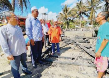 MOHD. Yaki Mohamed Zain (kanan) sugul semasa menceritakan kejadian kebakaran rumahnya kepada Mohd. Huzaimy Che Husin (dua dari kiri) di Kampung Perupuk, Bachok, Kelantan, semalam. –  FOTO/TOREK SULONG